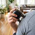 Mini percussion massage gun applied to the shoulder
