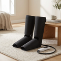 Pair of black calf and foot compression massage wraps with handheld controller on a rug in a living room